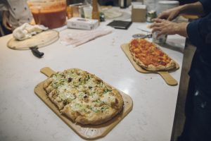 Two pinsas sitting on a kitchen counter with various toppings.