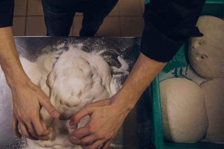 A chef kneading pizza dough.